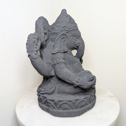 Gray stone statue of a deity on a white pedestal