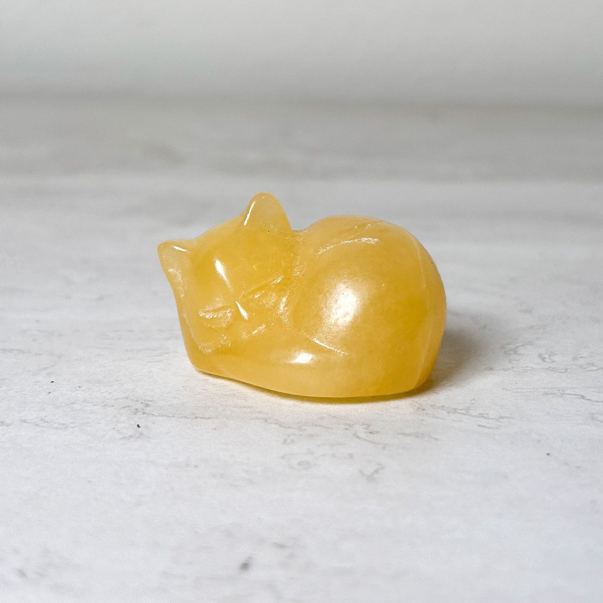 Polished yellow calcite sleeping cat crystal carving, view 8, at Ordinary Magic in Savannah, GA.