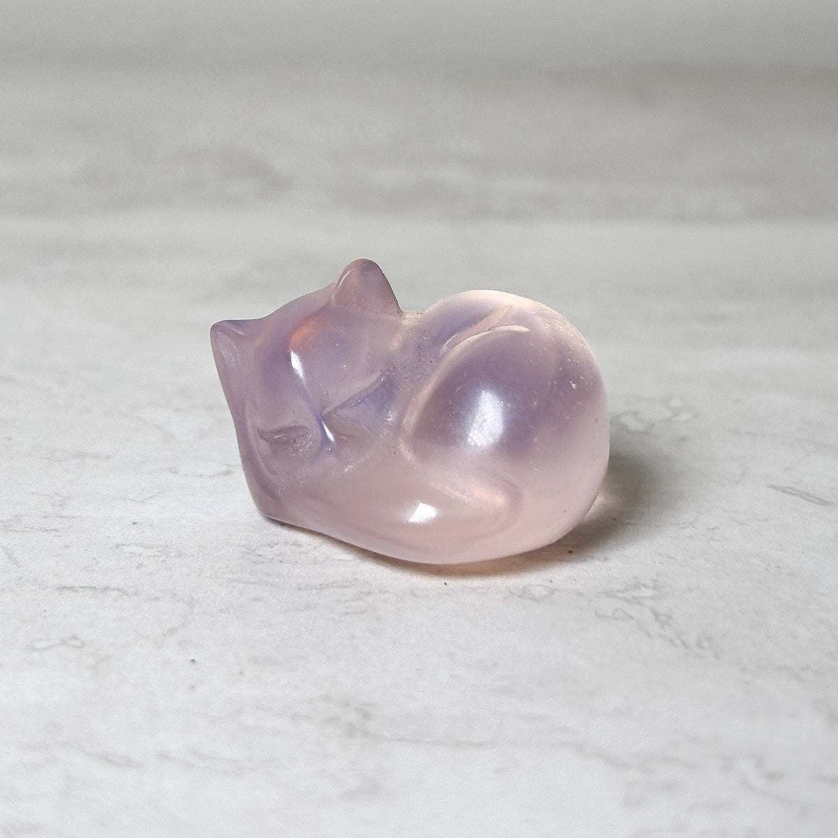 Sleeping cat crystal carving in purple amethyst, polished and curled in a sleeping pose, at Ordinary Magic in Savannah, GA.