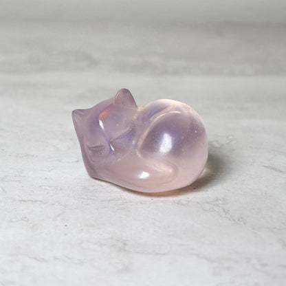 Sleeping cat crystal carving in purple amethyst, polished and curled in a sleeping pose, at Ordinary Magic in Savannah, GA.