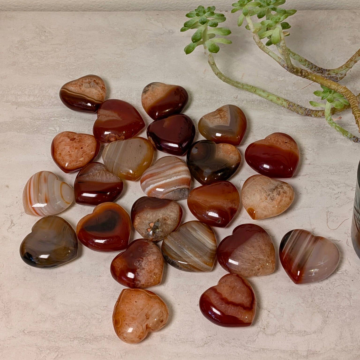Polished carnelian agate puff hearts in warm banded orange tones, 1 to 2 inches, at Ordinary Magic in Savannah, GA.