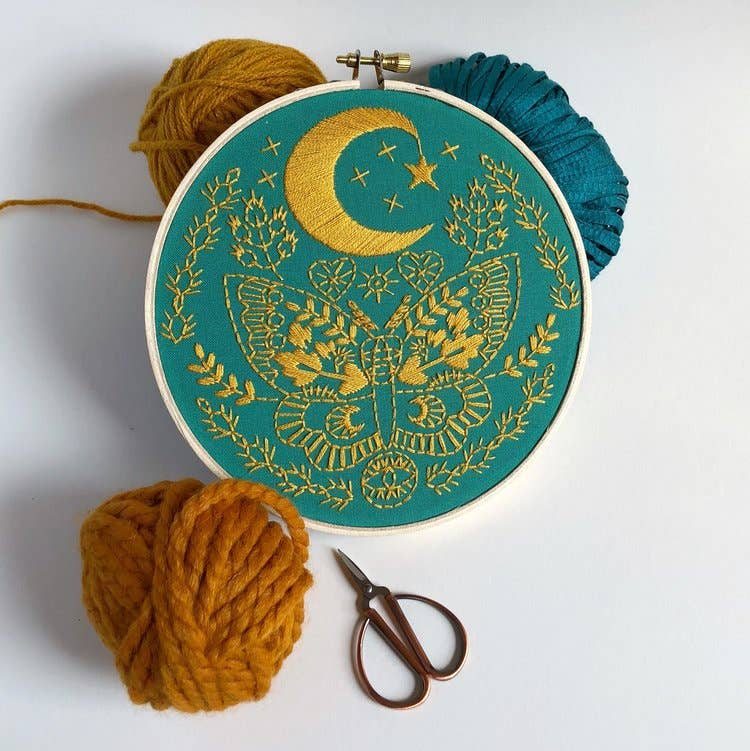 Lunar Moth Embroidery Kit by Rikrack, a celestial moth with crescent moon, stars and botanicals stitched in an embroidery hoop, at Ordinary Magic in Savannah, GA.