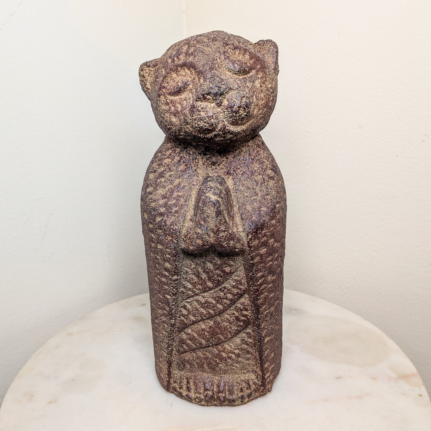 Stone sculpture of a figure with a bear-like head on a white pedestal