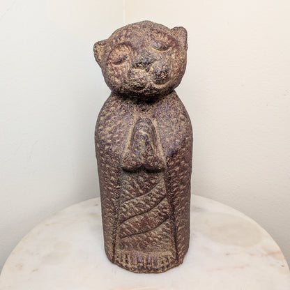 Stone sculpture of a figure with a bear-like head on a white pedestal