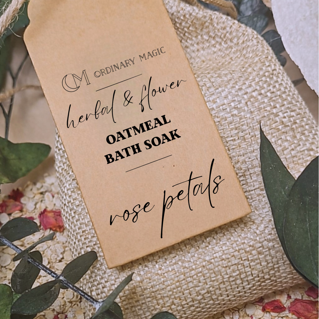 Kraft paper tag for 'Oatmeal Bath Soak with Rose Petals' by Ordinary Magic on a textured surface with green leaves and flowers.
