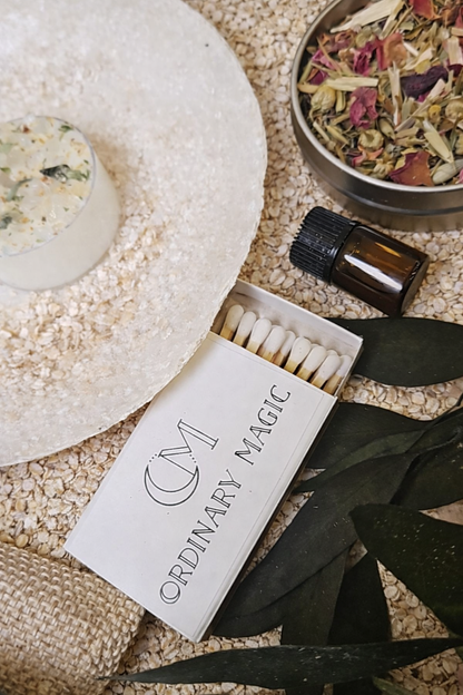 Matches labeled 'Ordinary Magic' with a small bowl of dried herbs on a textured surface.