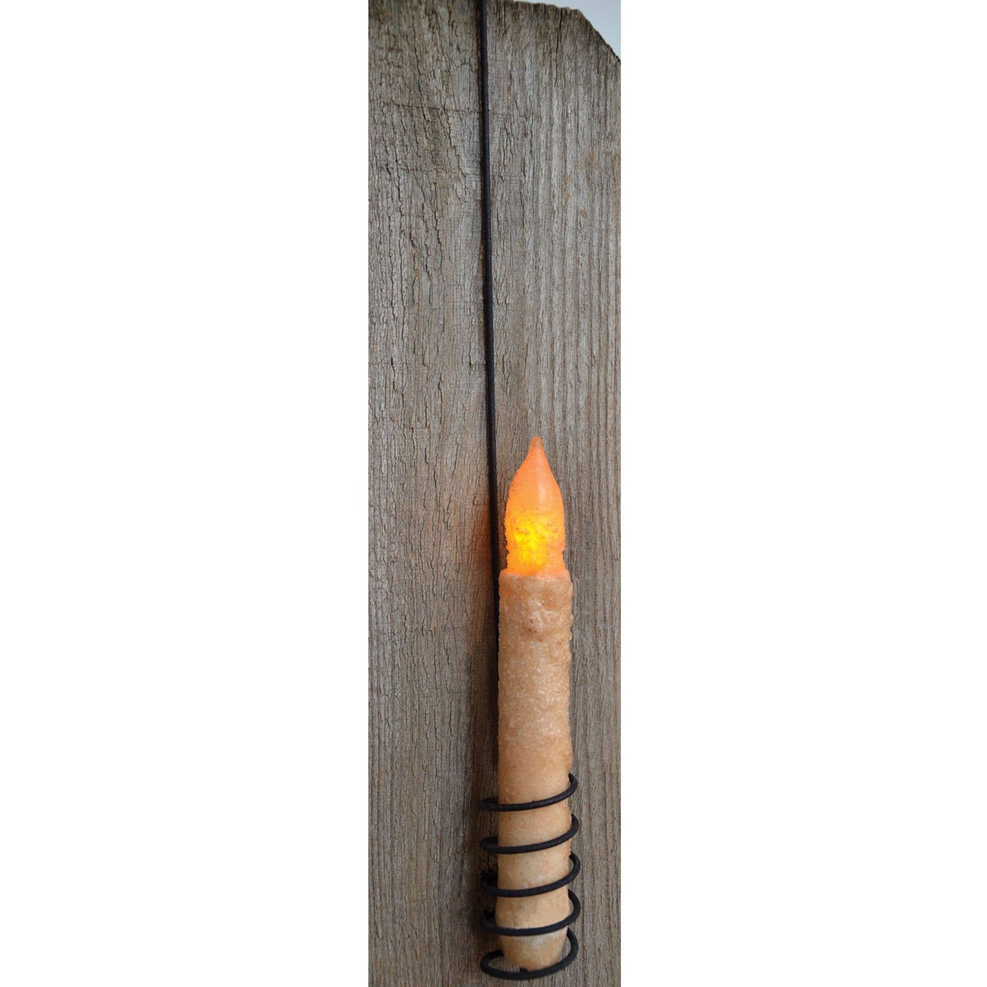 A rustic faux flameless LED candle mounted on a vertical weathered wood post, featuring a textured beige candle body, black wire wrap, and a glowing orange flame tip.
