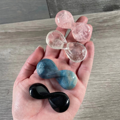 Carved crystal infinity symbols in obsidian, clear quartz, rose quartz, and trolleite