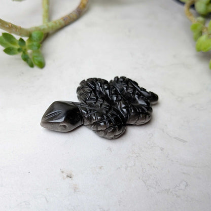 Carved crystal snake figure in silver sheen obsidian, at Ordinary Magic in Savannah, GA.