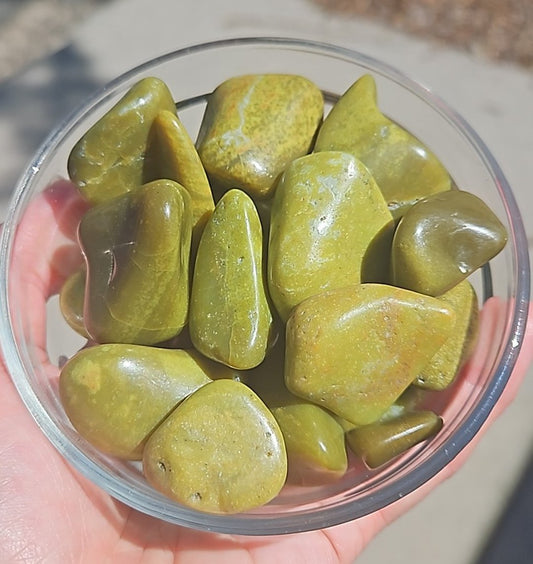 Green stones in a clear glass bowl held by a person