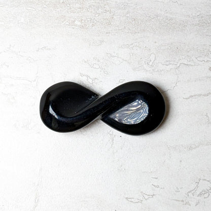 Black obsidian carved infinity symbol with a polished glossy finish
