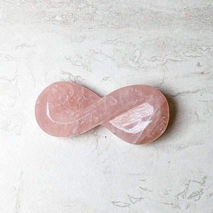 Rose quartz carved infinity symbol in soft pink