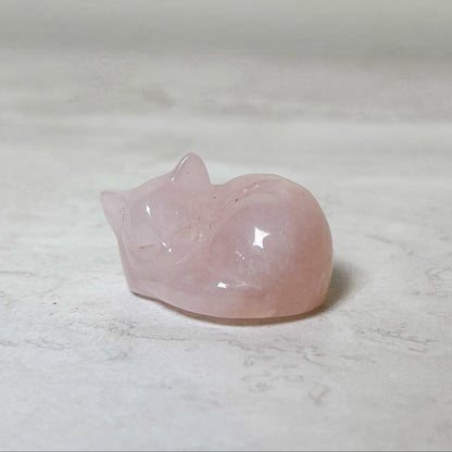 Sleeping cat crystal carving in pale pink rose quartz, polished and curled in a sleeping pose, at Ordinary Magic in Savannah, GA.