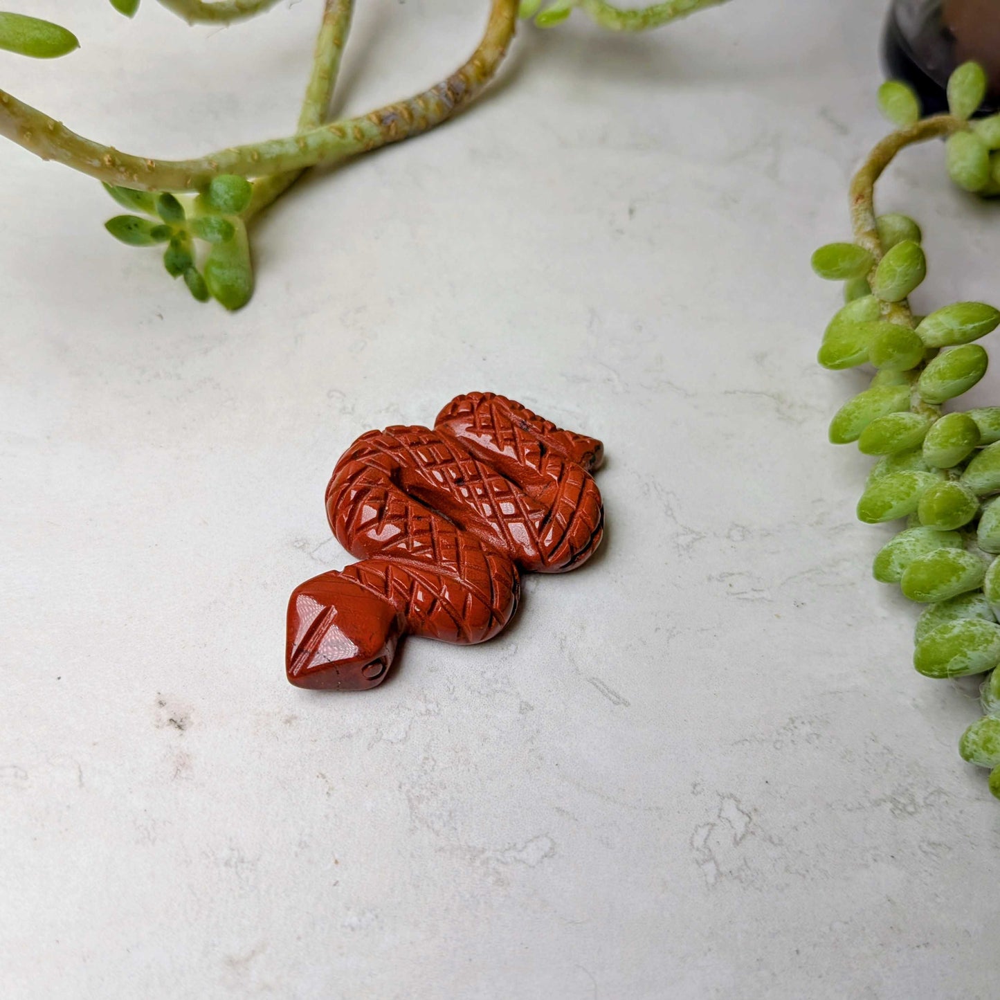 Carved crystal snake figure in red jasper, at Ordinary Magic in Savannah, GA.