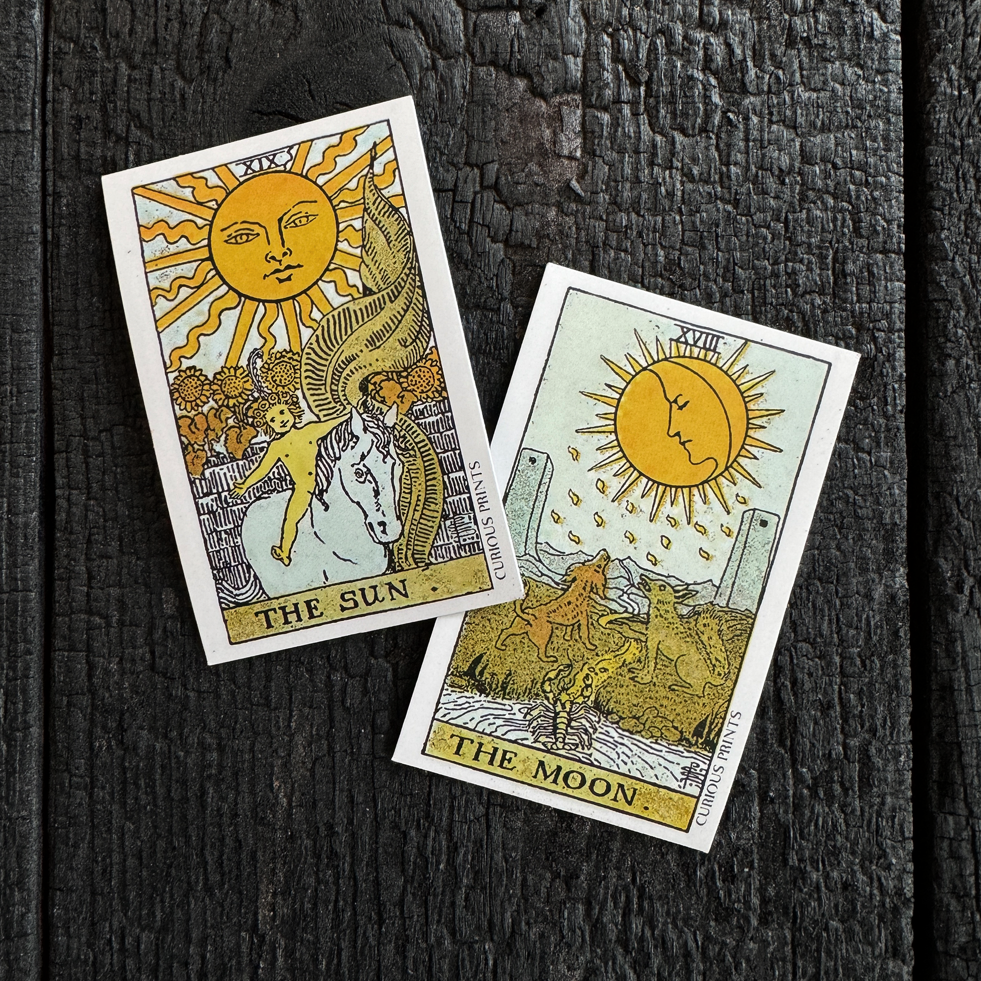 Two tarot cards titled 'The Sun' and 'The Moon' on a textured black surface.