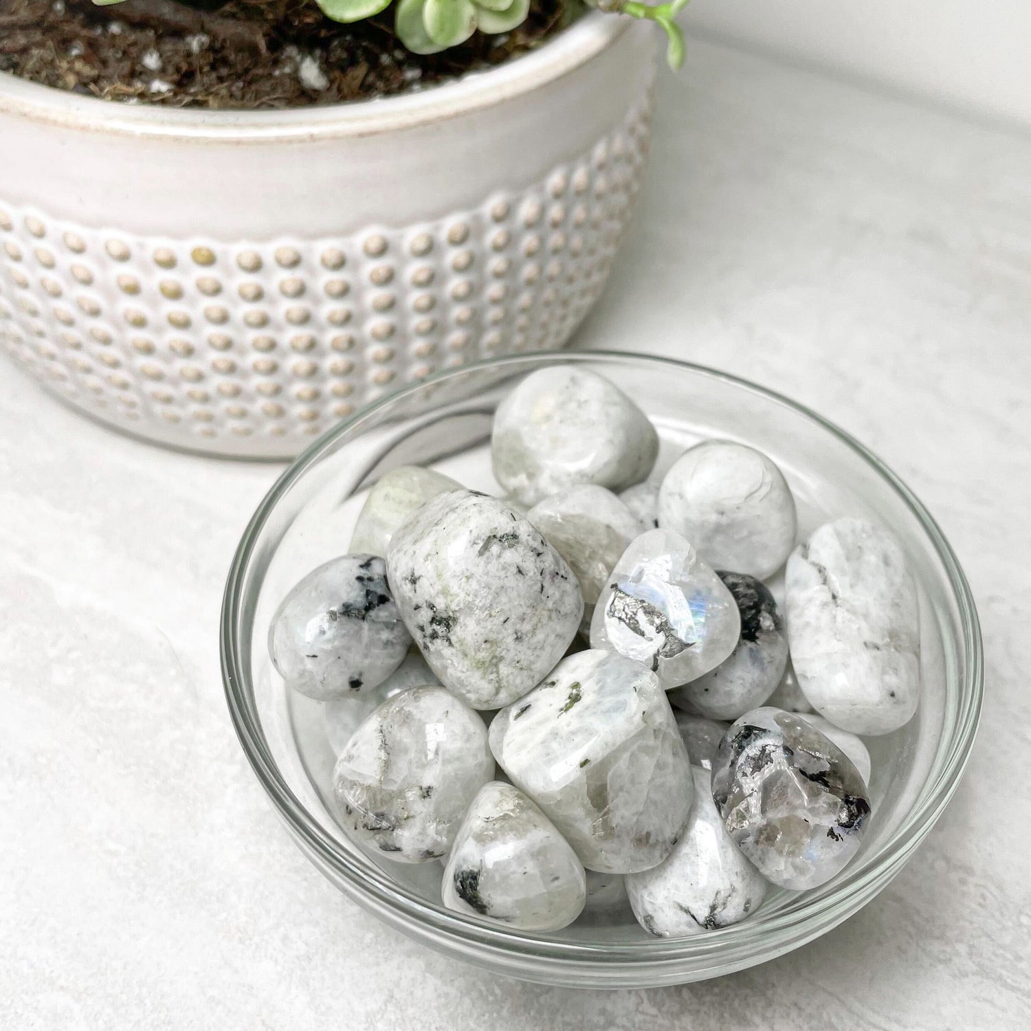Tumbled rainbow moonstone with a milky white surface and blue flash.